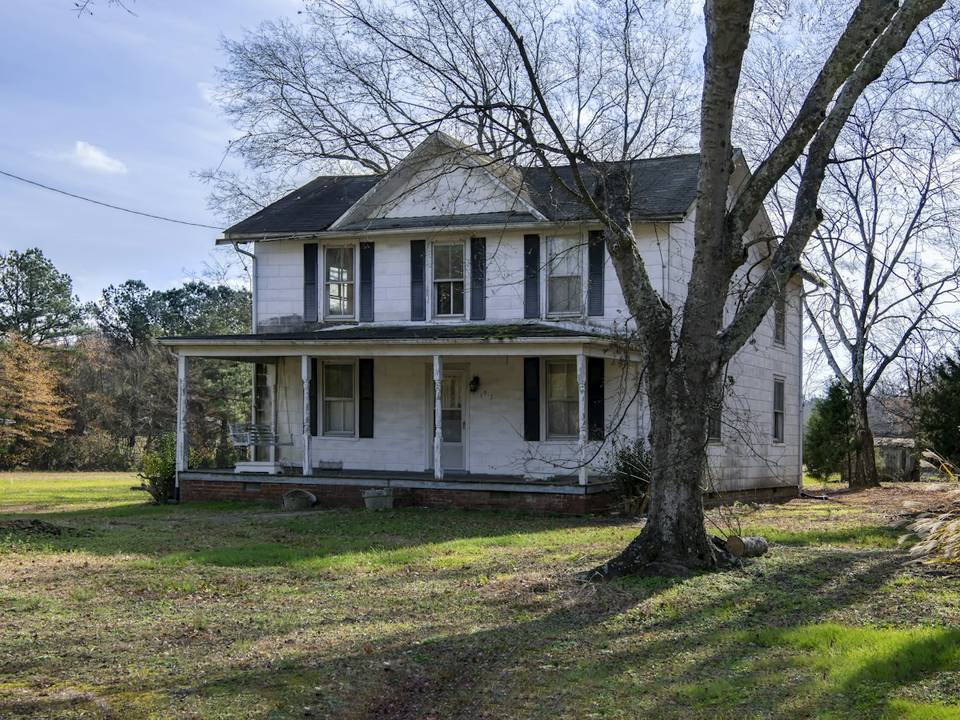 Older two story farmhouse with a wraparound porch
